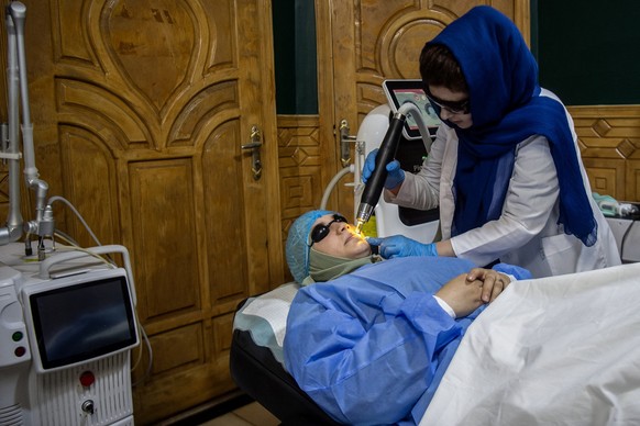 In this photograph taken on August 31, 2025, a member of the medical staff performs laser treatment on an Afghan woman&#039;s face at a beauty clinic in Kabul. Decked with fake crystal chandeliers and ...