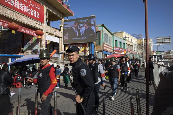 Des policiers chinois patrouillent dans la rue, dans la région du Xinjiang.