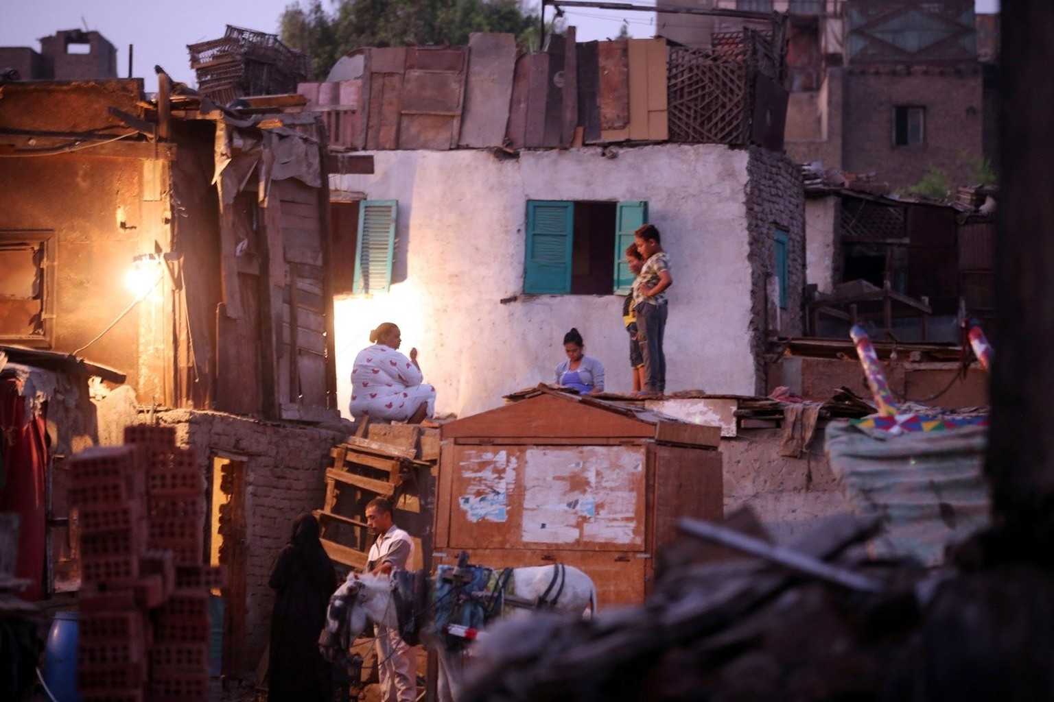 epa05507594 A picture made available on 23 August 2016 showing Egyptians sitting outside their houses at a slum near the Nile City Towers in Ramlet Bulaq neighborhood, Cairo, Egypt, 21 August 2016. Ra ...