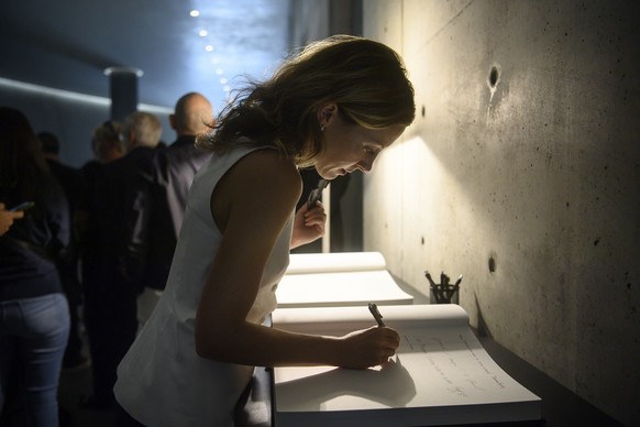 A person signs a condolence book as people line up to pay respects to designer Giorgio Armani lying in state at the Armani/Teatro in Milan, northern Italy, Saturday, Sept. 6, 2025. (Claudio Furlan/LaP ...