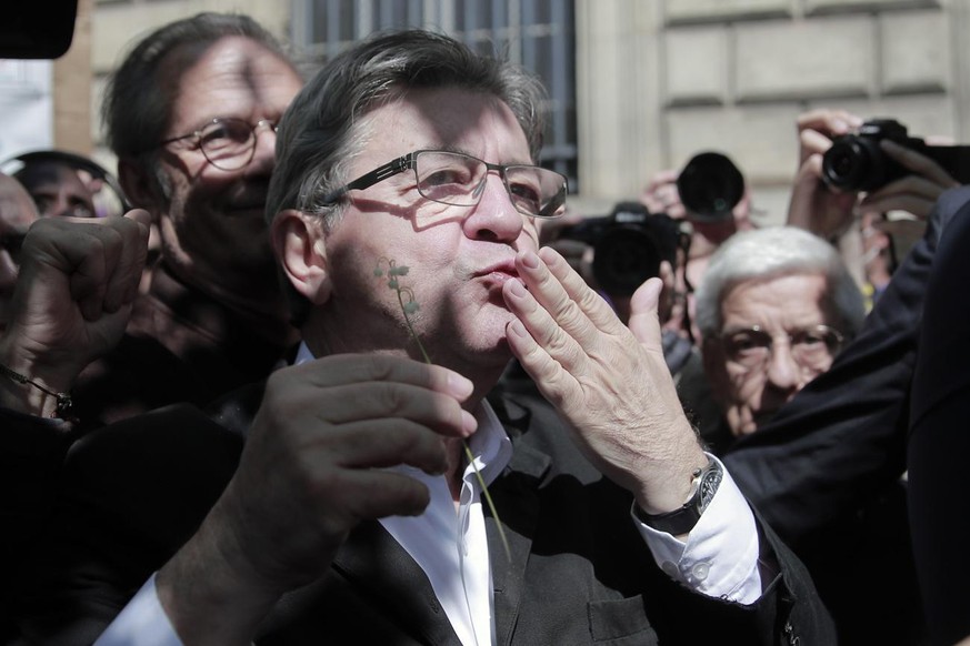 French far-left party leader and former candidate for the presidential election Jean-Luc Melenchon holds a Lilly of the Valley flower and blows kisses during a May Day demonstration march from Republi ...