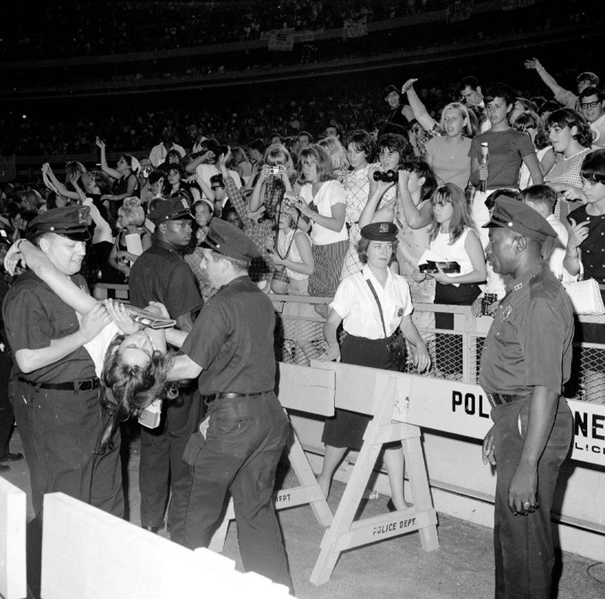 UNITED STATES - AUGUST 15: No doubt overcome by the soulful renderings, this teenager is carried off after fainting during the Beatles concert at Shea Stadium. (Photo by Jim Hughes/NY Daily News Archi ...