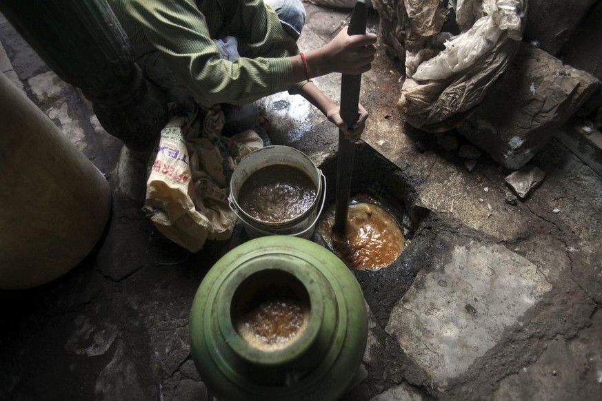 An Indian boy mixes raw material for preparing Gudumba, local illicit liquor in the southern Indian state of Andhra Pradesh, in Dhoolpet area of Hyderabad, India, Friday, Dec. 16, 2011. At least 170 p ...