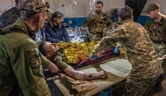 Des médecins militaires préparent un soldat ukrainien blessé pour le transporter vers un hôpital, dans la région de Lougansk, en mai 2022.