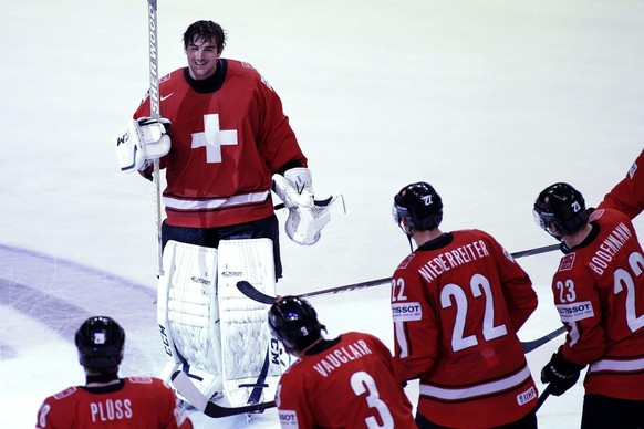 Switzerland&amp;#039;s goaltender Reto Berra, top, is celebrated by his teammates, from left, Martin Pluess, Julien Vauclair, Nino Niederreiter and Simon Bodenmann, after their victory over USA, durin ...