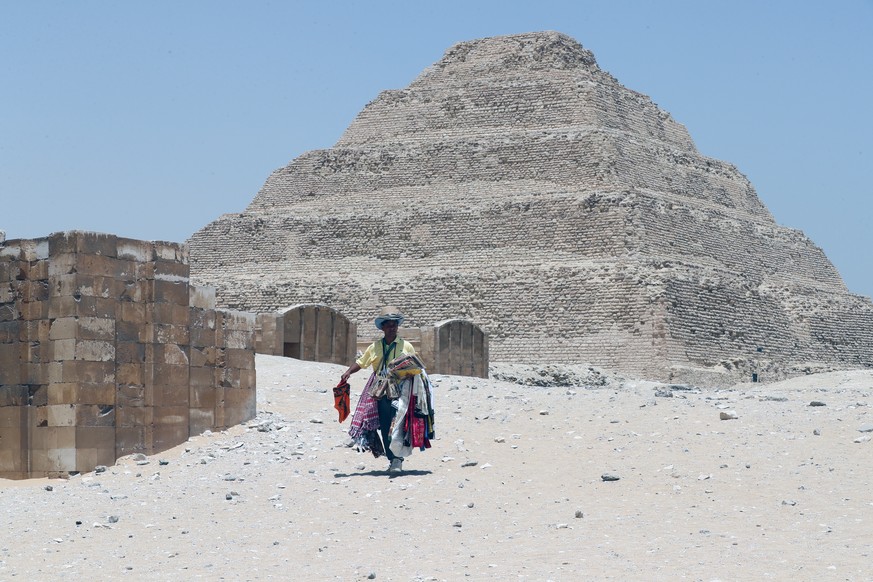epa09986849 An Egyptian souvenir vendor walks near the King Djoser&#039;s Step Pyramid, also known as the &#039;Saqqara pyramid&#039;, in the Saqqara area of Giza, Egypt, 30 May 2022. A collection of  ...