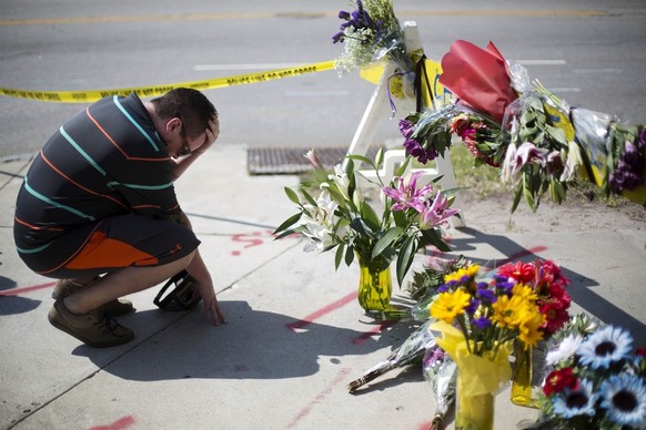 Noah Nicolaisen, of Charleston, S.C., kneels at a makeshift memorial down the street from where a white man opened fire Wednesday night during a prayer meeting inside the Emanuel AME Church killing se ...