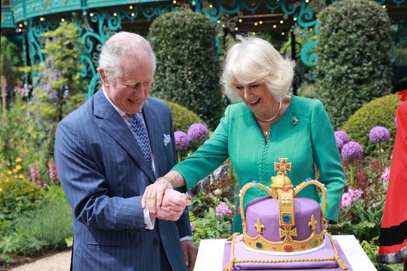 NEWTOWNABBEY, NORTHERN IRELAND - MAY 24: King Charles III and Queen Camilla laugh as they cut a cake during a visit to open the new Coronation Garden on day one of their two-day visit to Northern Irel ...