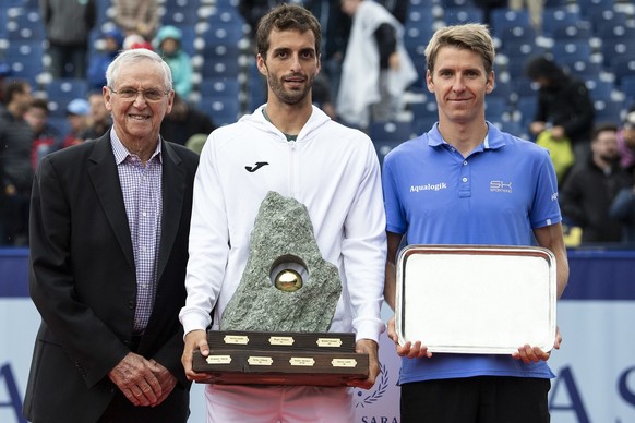 Albert Ramos-Vinolas of Spain, winner, center, and Cedrik-Marcel Stebe of Germany, right, and tennis former Roy Emerson of Australia, left, celebrate with the trophy after the final game at the Swiss  ...