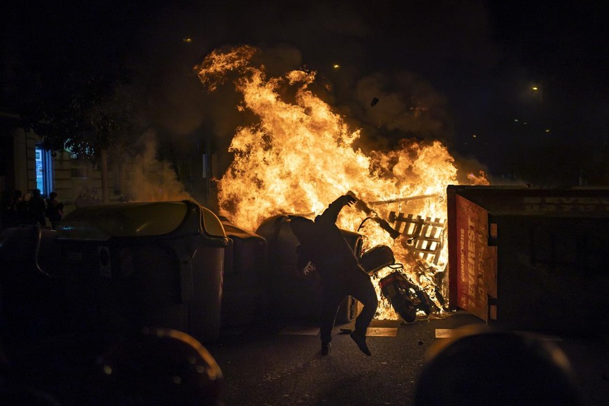 A demonstrator throws an object towards police during clashes following a protest condemning the arrest of rap singer Pablo Hasél in Barcelona, Spain, Thursday, Feb. 18, 2021. Protests over the impris ...