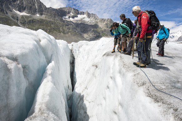 Tourists observe a crevasse during a guided tour on the Aletsch glacier, in Fiesch, Switzerland, Tuesday, July 28, 2015. With 23 kilometers is the Aletsch glacier the longest glacier of Europe and bel ...