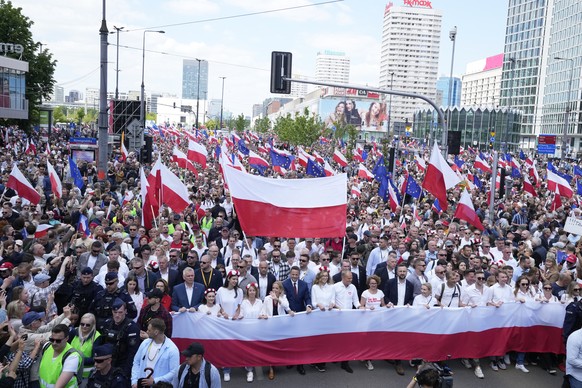 The liberal presidential candidate Rafal Trzaskowski holds a giant polish flag in the first row as he stands next to a waving women during a march one week ahead of a decisive presidential election in ...