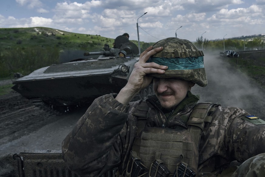 A Ukrainian soldier holds his helmet as he rides an APC in Bakhmut, in the Donetsk region, Ukraine, Wednesday, April 26, 2023. (AP Photo/Libkos)