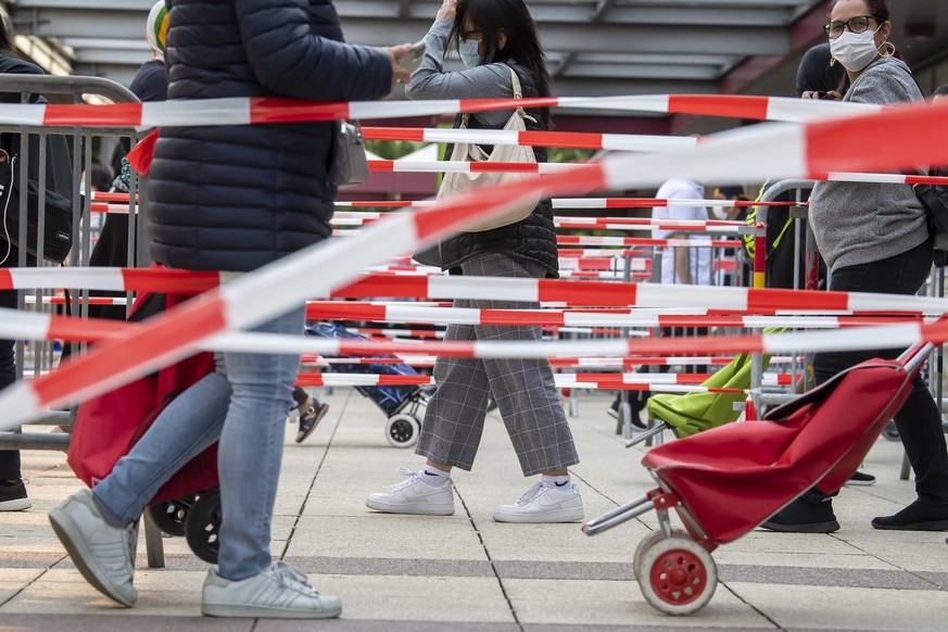 People queue to receive bags with free food and essential products received from donations at the ice stadium Les Vernets, in Geneva, Switzerland, Saturday, May 23, 2020. Following the pandemic corona ...