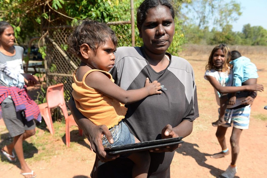 epa04297627 Tara Black holds her 18-month old daughter Nevaeh Dickson, as well as an iPad an in the aboriginal community of Peppimenarti, about 320km south-west of Darwin, Australia, 04 July 2014. Pep ...