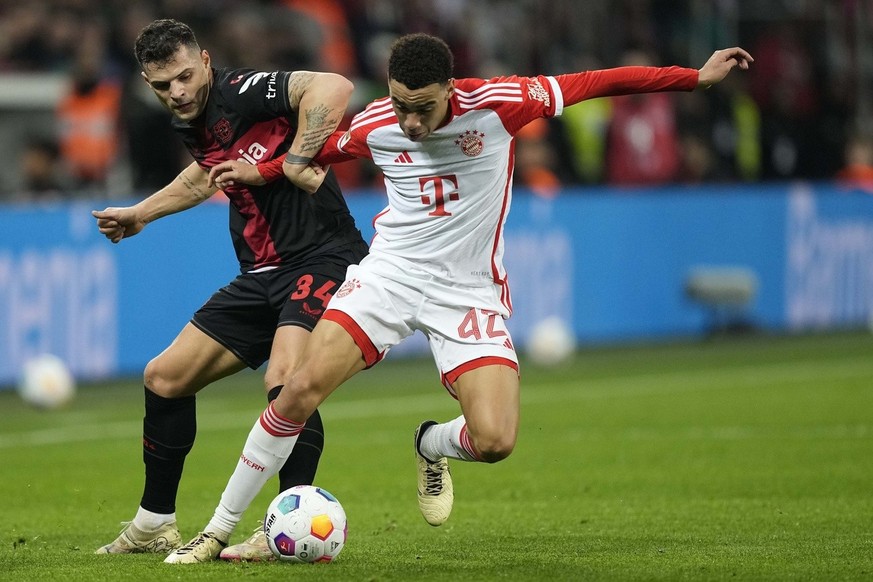 Leverkusen&#039;s Granit Xhaka, left, and Bayern&#039;s Jamal Musiala challenge for the ball during the German Bundesliga soccer match between Bayer 04 Leverkusen and FC Bayern Munich at the BayArena  ...