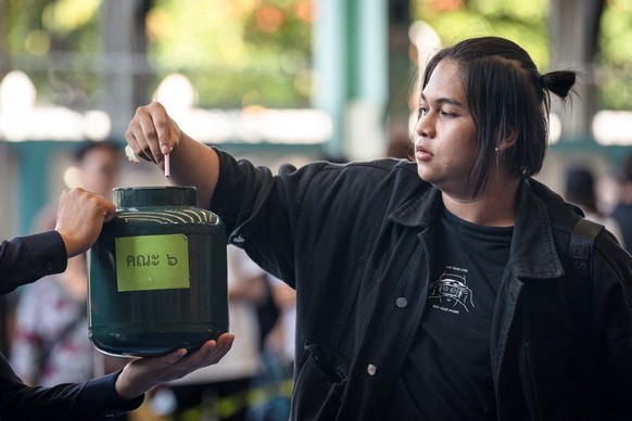 A man picks a black ballot, meaning exemption from service, during the Thai military conscription drawing at Watmatchantikaram School in Bangkok on April 7, 2026. (Photo by chanakarn LAOSARAKHAM / AFP ...