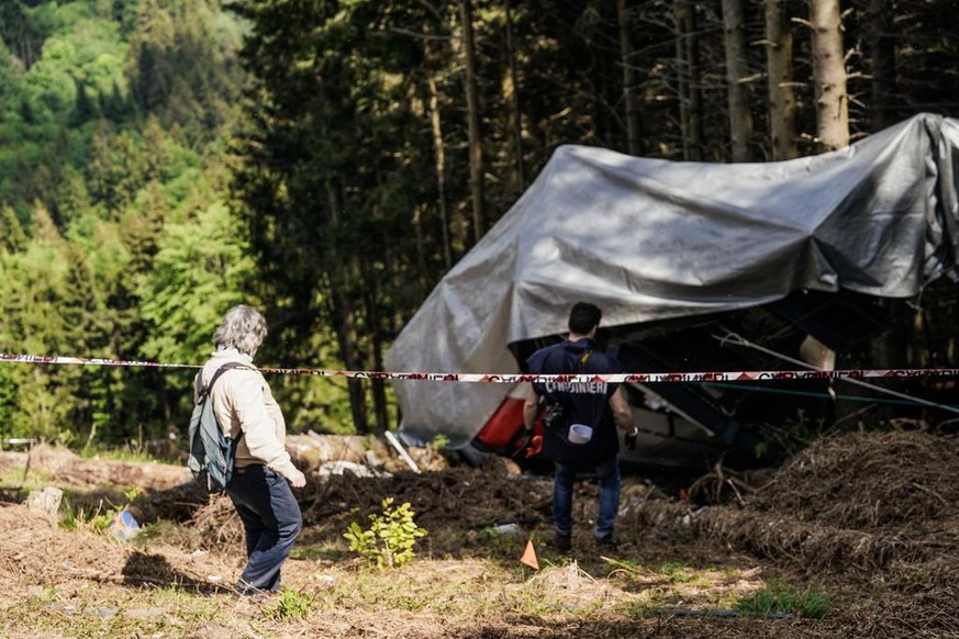 epa09231482 The technical consultant (C), flanked by Italian carabinieri, visits the site of the Mottarone cable car accident, in Stresa, Italy, 27 May 2021. At least 14 people were killed after a Str ...