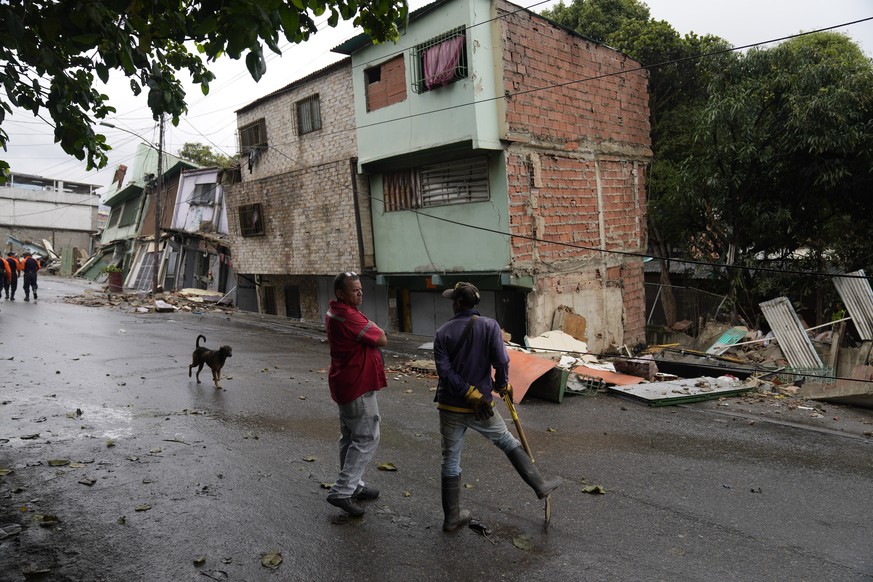 City hall workers stand in front of a collapsed home, which fill during heavy rain in the Catia neighborhood of Caracas, Venezuela, Wednesday, April 27, 2022. About 10 houses collapsed the previous da ...