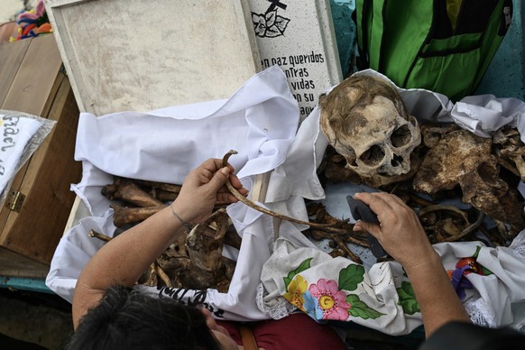 A woman prepares to clean the remains of a relative ahead of Day of the Dead celebrations at the Pomuch cemetery, Campeche state, Mexico on October 18, 2025. The cleansing ritualówhich combines Mayan  ...