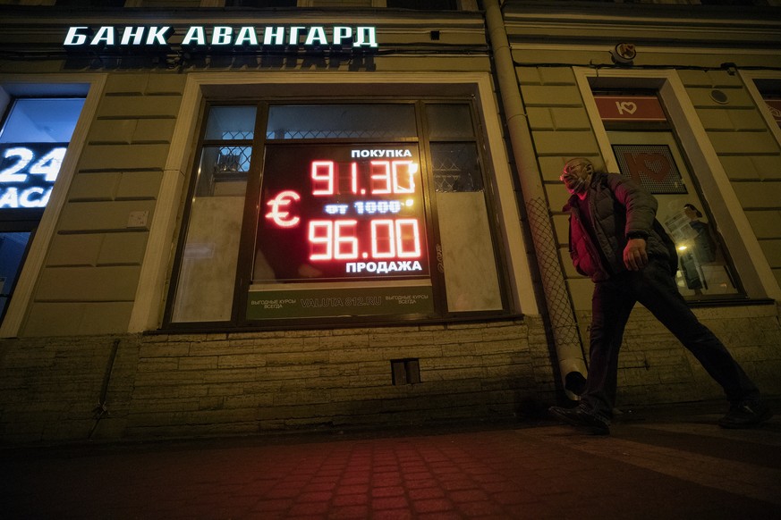 epa09785374 A man walks in front of digital panel displaying the euro currency rate at an exchange office in St. Petersburg, Russia, 25 February 2022. The dollar and the euro are confidently rising on ...