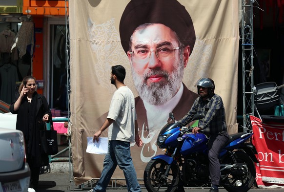 epa12918542 Iranians walk past a poster of Iranian supreme leader Ayatollah Mojtaba Khamenein in Tehran, Iran, 28 April 2026. US President Donald Trump announced that a ceasefire between the US and Ir ...