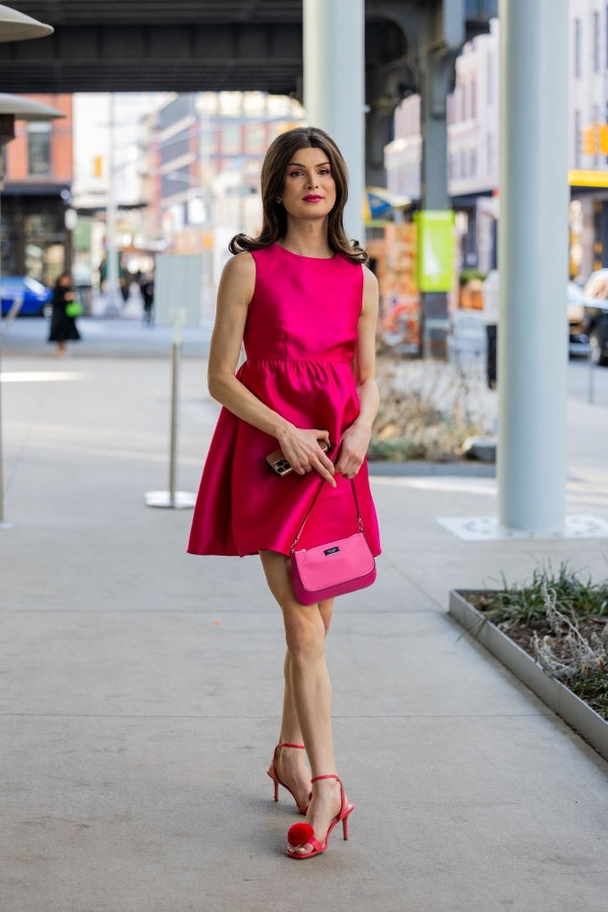 NEW YORK, NEW YORK - FEBRUARY 10: Dylan Mulvaney wears pink tailored sleeveless silk skirt, bag, heeled sandals outside Kate Spade during New York Fashion Week on February 10, 2023 in New York City. ( ...
