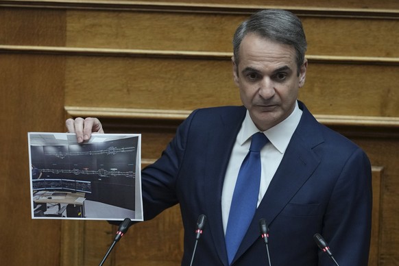 Greek Prime Minister Kyriakos Mitsotakis holds up a photograph of a new railway control facility during his speech in parliament, ahead of the submission of a no-confidence motion by opposition partie ...