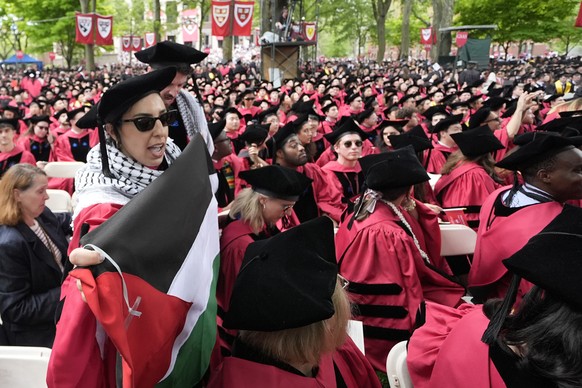 Graduating students chant as they depart commencement in protest to the 13 graduating seniors who were not allowed to participate due to protest activities, in Harvard Yard during commencement at Harv ...