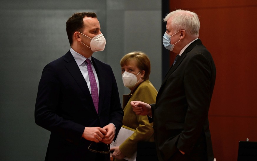 German Chancellor Angela Merkel, center, looks on as German Health Minister Jens Spahn, left, and German Interior Minister Horst Seehofer talk prior to the weekly cabinet meeting in Berlin on March 17 ...