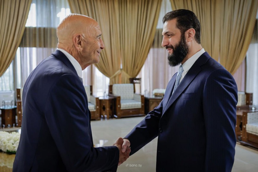 In this photo released by the Syrian official news agency SANA, U.S. Ambassador to Turkey and Special Envoy to Syria Tom Barrack, left, shakes hands with Syria's President Ahmad al-Sharaa, in Dam ...