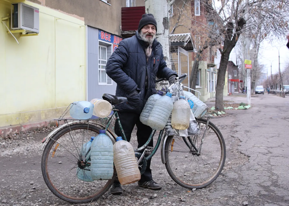 L'homme aux yeux fatigués : il a mis de l'eau potable dans les bouteilles en plastique accrochées à son vélo.