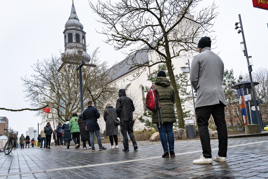 epa09654927 A long queue for a quick test in the center of Aalborg at the test site at Budolfi Church, in Aalborg, Denmark, 23 December 2021. It is free to get a quick test against covid-19 in Denmark ...