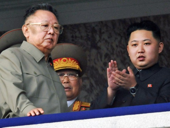 FILE - In this Oct. 10, 2010 file photo, North Korea leader Kim Jong Il, left, walks by his son Kim Jong Un, right, on the balcony as they attend a massive military parade marking the 65th anniversary ...