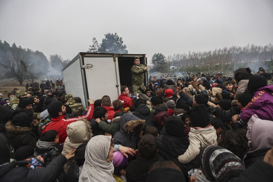 epa09577079 Migrants gather for geting humanitarian aid spread by Belarusian militaries at the camp at the Belarus-Polish border in the Grodno region, not far from the checkpoint Bruzgi, Belarus, 11 N ...