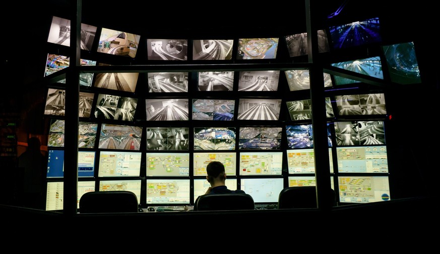 Saint Petersburg, Russia - December 9, 2019: Rear view of man looking at multiple computer screens. Monitoring system with multiple displays on the exhibition of Grand maket Russia layout. xkwx techno ...