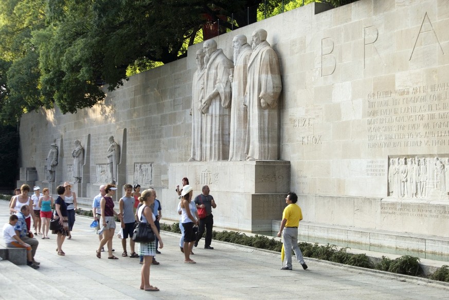 Touristen besuchen mit einem Touristenfuehrer die Mauer der Reformatoren im Parc des Bastions in Genf, Schweiz, aufgenommen am 20. Juli 2006. (KEYSTONE/Gaetan Bally)

Tourists visit with a tour guide  ...