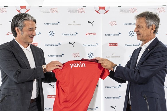 Swiss soccer coach Murat Yakin, left, holds a shirt of the Swiss national soccer team next to Dominique Blanc, president of the Swiss football federation SFV, at a press conference where he is present ...