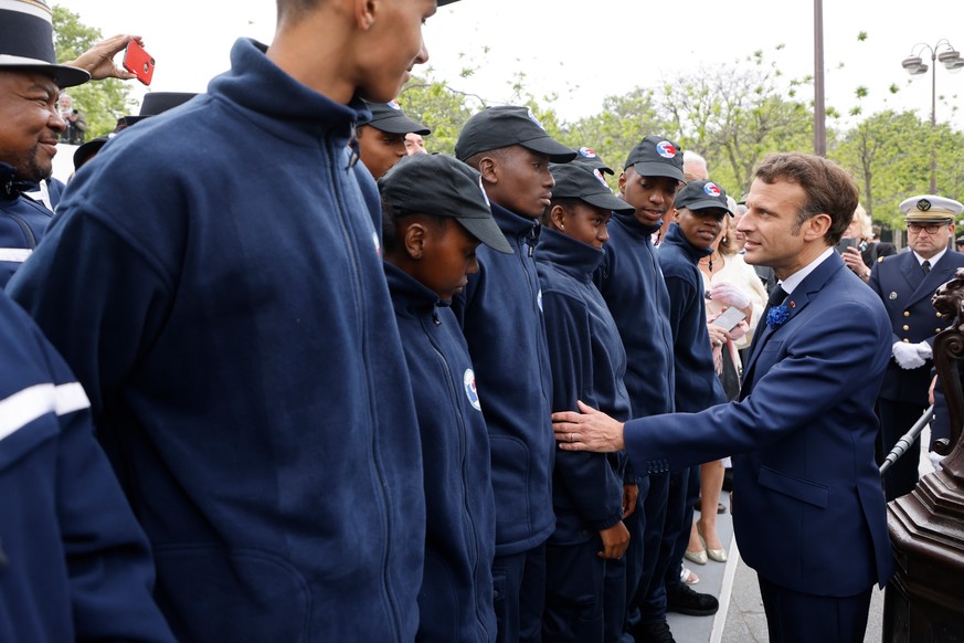 epa09933269 France&#039;s President Emmanuel Macron (R) greets cadets of the mayotte gendarmerie (L) at the Arc de Triomphe as they attend the ceremonies marking the Allied victory against Nazi German ...