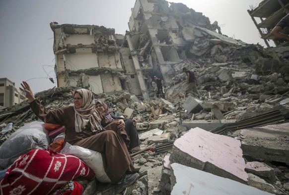 epa11286402 Palestinian women sit among the rubble of a house after returning to Al Nusairat refugee camp following the Israeli army?s withdrawal from the area, southern Gaza Strip, 18 April 2024. Mor ...