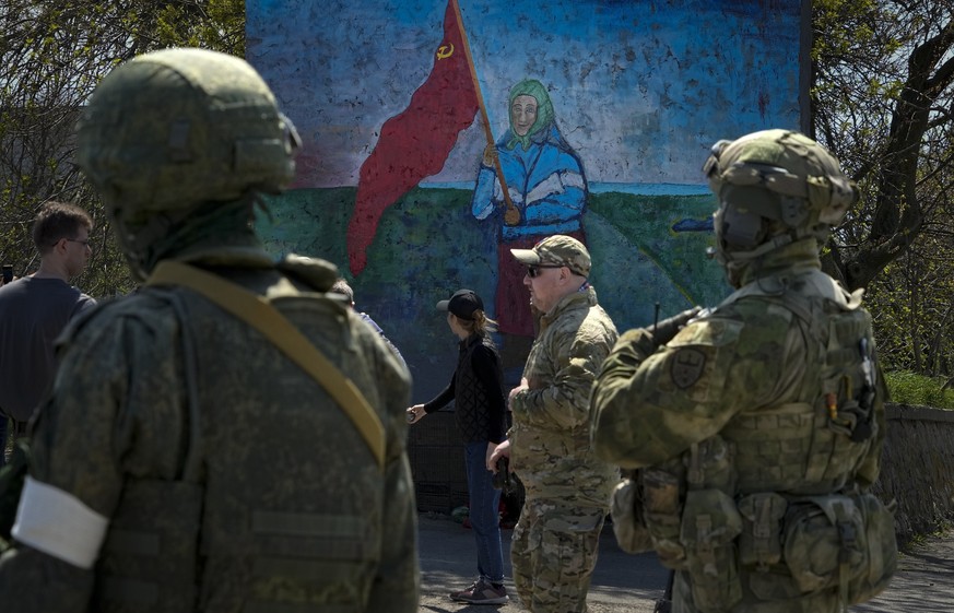 FILE - Russian servicemen stand near a painting of a Ukrainian woman holding a Soviet-era red flag in territory under the government of the Donetsk People&#039;s Republic, eastern Ukraine, April 30, 2 ...