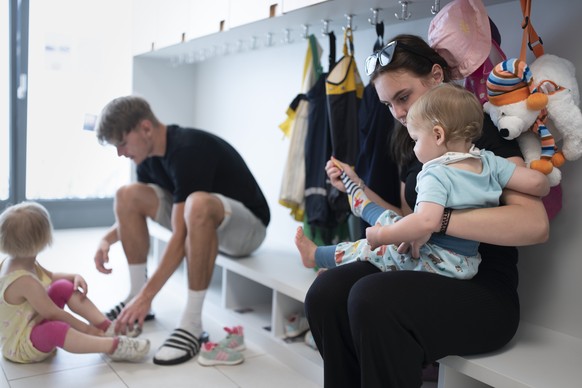 THEMENBILD ZUR LANCIERUNG DER KITA-INITIATIVE --- Betreuungspersonal hilft Kleinkindern beim Anziehen der Schuhe und Sonnenschutzkleidung, bevor es zum Spielen in den Aussenbereich der Kita 6a der Sti ...