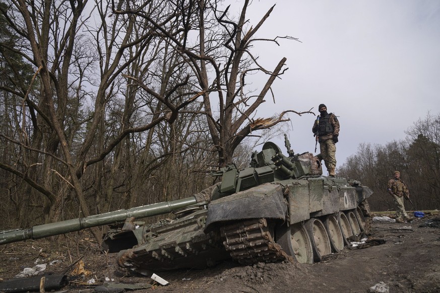 A Ukrainian serviceman stands atop on destryed Russian tank in Chernihiv region, Ukraine, Friday April 8, 2022. (AP Photo/Evgeniy Maloletka)