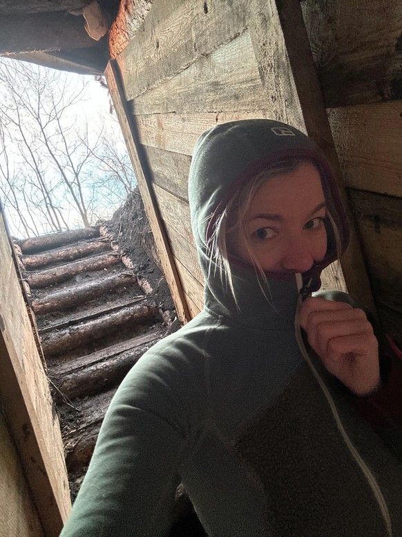 Ukraine, région d'Izium, la journaliste Maria Steinmayr se prend en photo devant l'entrée d'un bunker semi-enterré.
