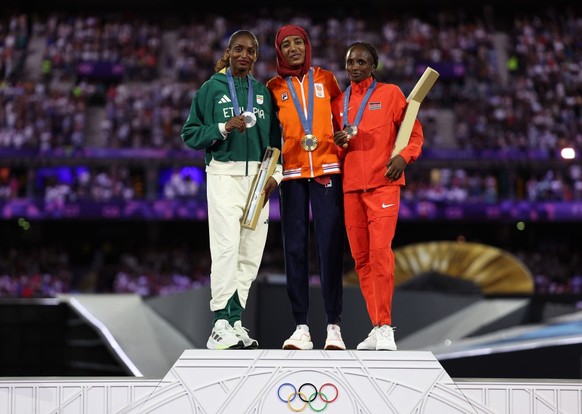 PARIS, FRANCE - AUGUST 11: Gold medalist Sifan Hassan of Team Netherlands (C), Silver medalist Tigst Assefa of Team Ethiopia (L) and Bronze medalist Hellen Obiri of Team Kenya (R) celebrate on the pod ...