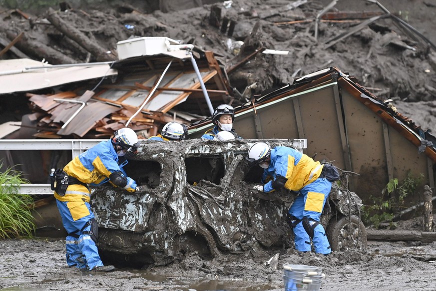 Rescuers check a damaged vehicle at the site of a mudslide in Atami, Shizuoka prefecture, southwest of Tokyo, Sunday, July 4, 2021. A gush of mud swept away homes and cars in the resort town. (Kyodo N ...