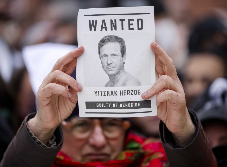 Un manifestant tient une pancarte représentant le président israélien Isaac Herzog, l'accusant de génocide.