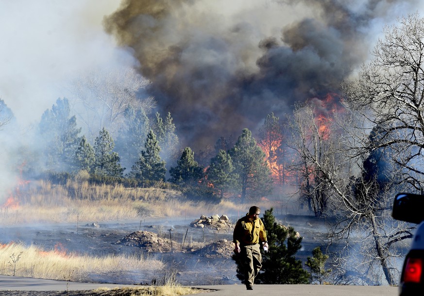 A firefighter walks up a road near a home at Middle Fork Road and Foothills Highway north of Boulder, Colo., on Thursday, Dec. 30, 2021. (Cliff Grassmick/Daily Camera via AP)