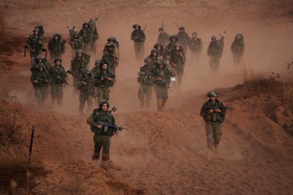 A column of Israel troops walk on a dirt road as they approach the fence marking the border between Lebanon and Israel near the border village of Malkiya in this Tuesday, Aug. 15, 2006 file photo. Isr ...
