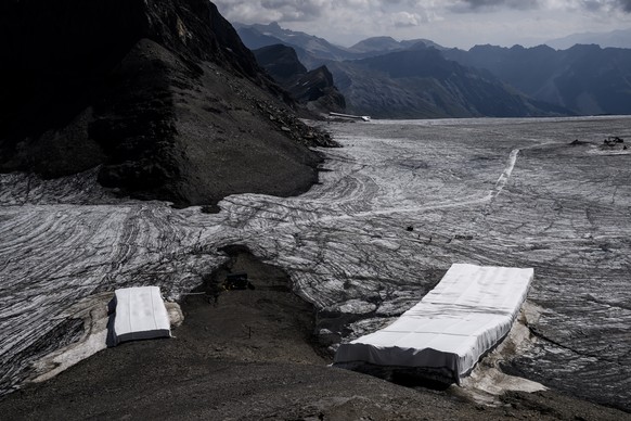 epa10095456 Hikers walk in front of snow from the last winter season covered with blankets to prevent it from melting due to global warming on the Scex Rouge Glacier and Tsanfleuron Glacier at the &#0 ...